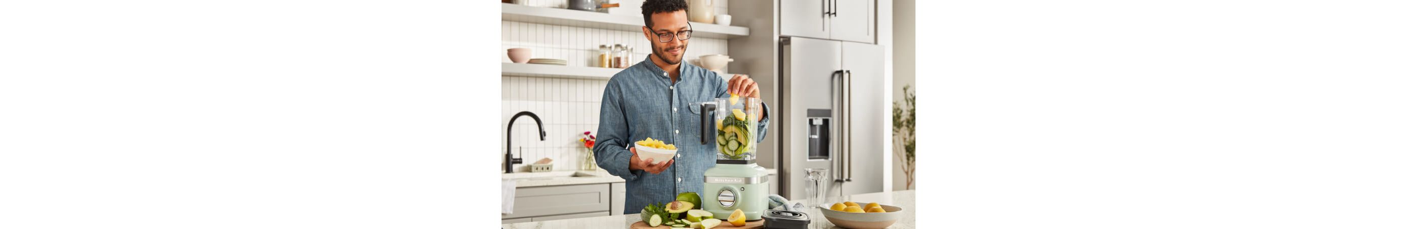 A man adding fruit to a KitchenAid® blender.