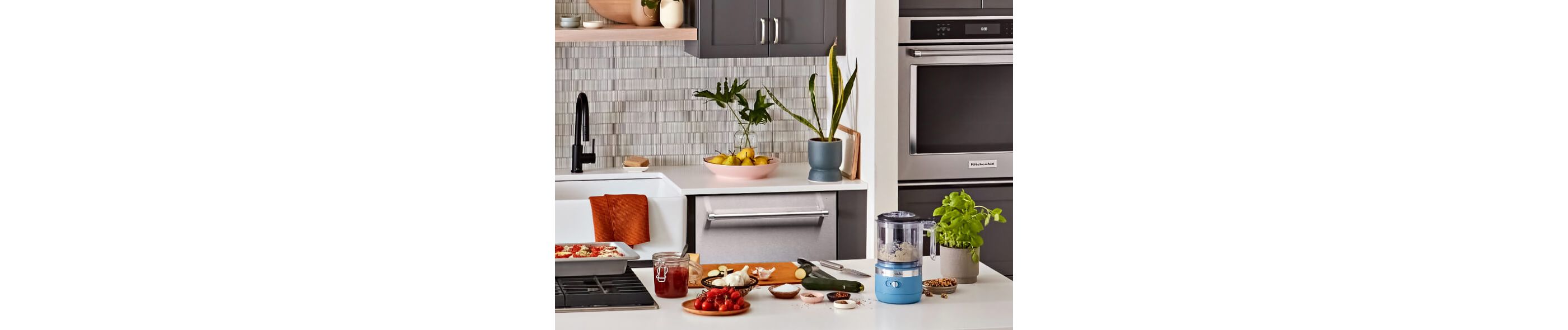 A kitchen featuring a KitchenAid® wall oven, dishwasher and countertop mini food processor.