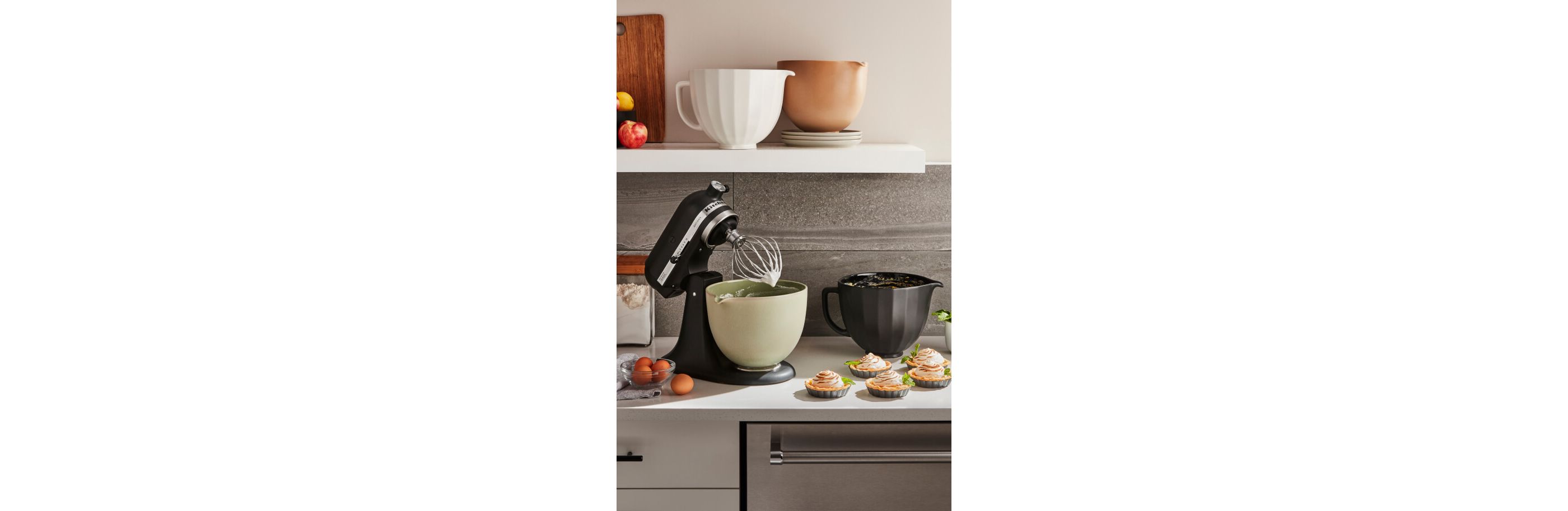 A black KitchenAid® stand mixer surrounded by mini tarts.