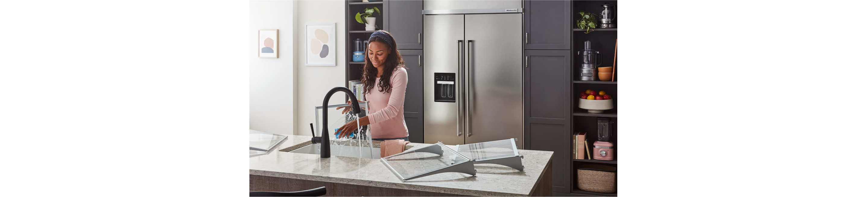 A maker washing the interior bins and shelves of a KitchenAid® Built-In Side-by-Side Refrigerator