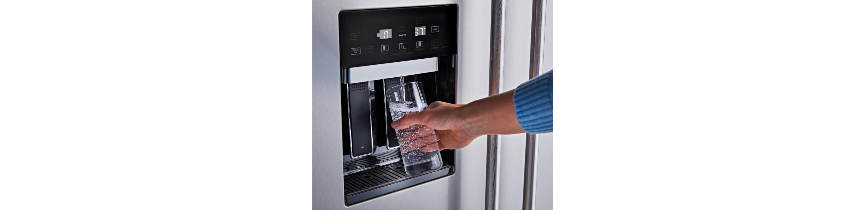 A person filling a glass of water with the External Water Dispenser on the KitchenAid® Built-In Side-by-Side Refrigerator