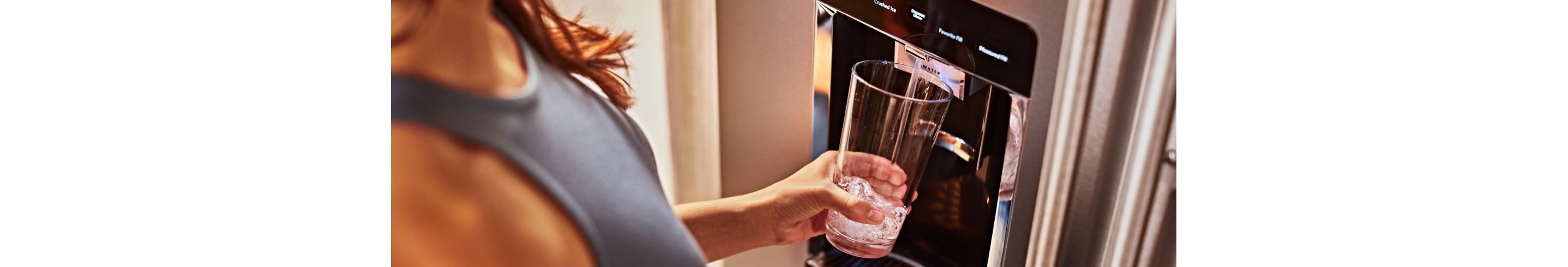 Filling a glass from a KitchenAid® refrigerator water dispenser.