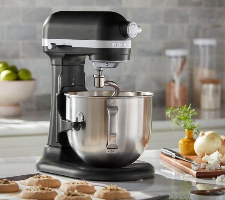 A Black KitchenAid® Bowl-Lift Stand Mixer next to different pastries and freshly baked chocolate chip cookies on baking sheets.