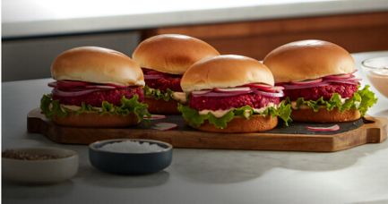 A blue KitchenAid® Bowl-Lift Stand Mixer on a countertop near beetroot burgers and prepared beetroot burgers on a cutting board.