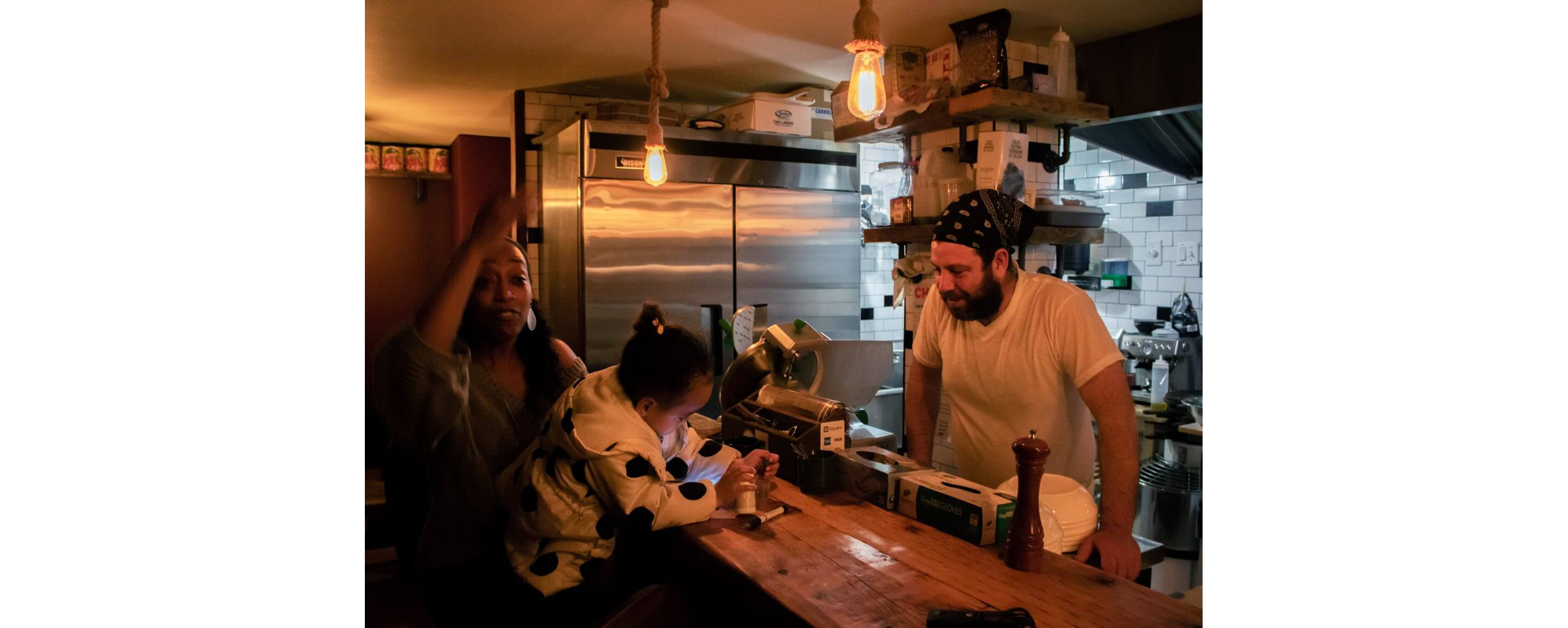 A man standing behind the register helping his two customers finish paying the tab.