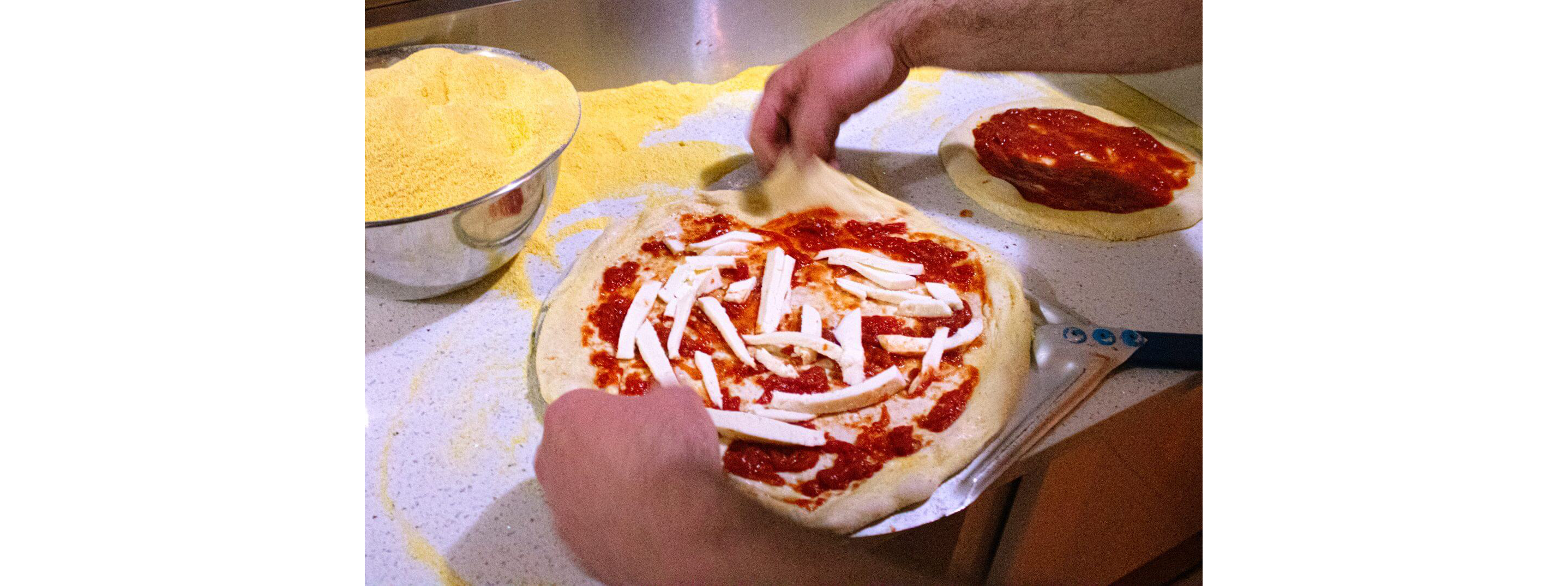 Experienced hands preparing a pizza from scratch.
