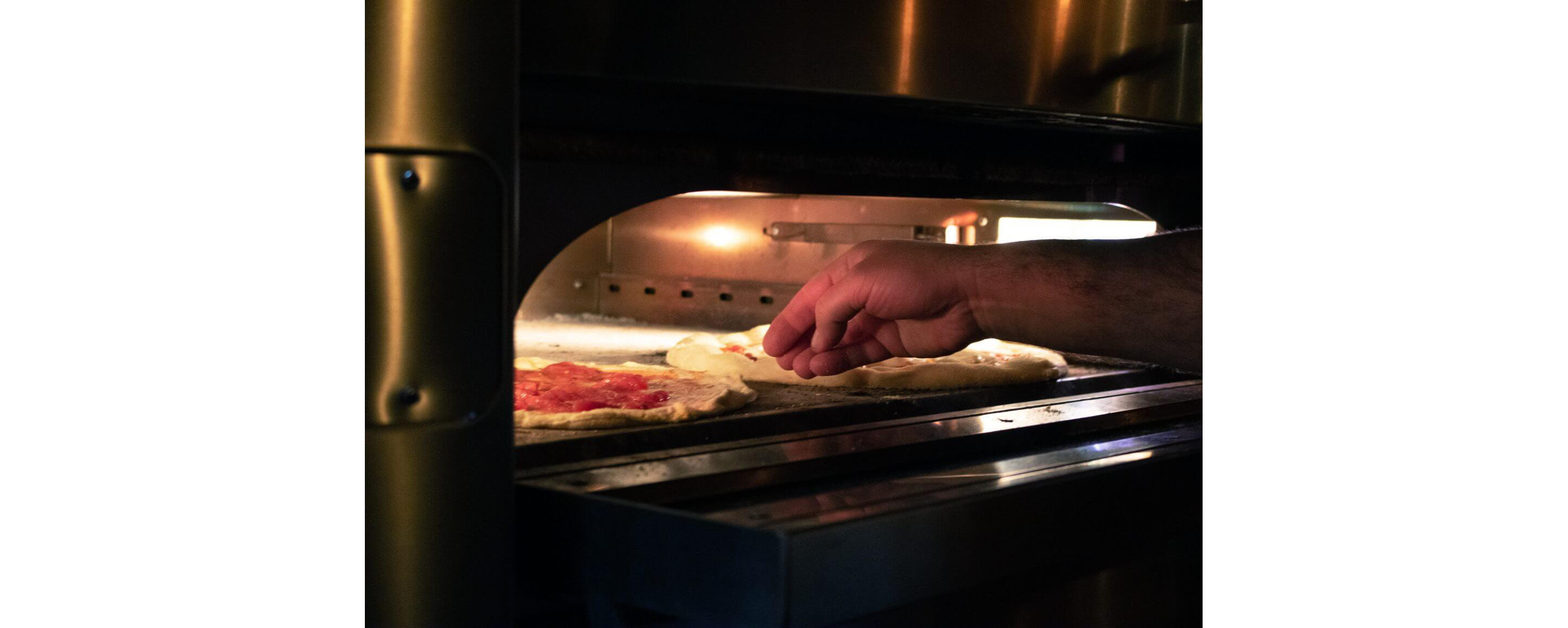 Two freshly made pizzas resting in a stainless steel pizza oven.