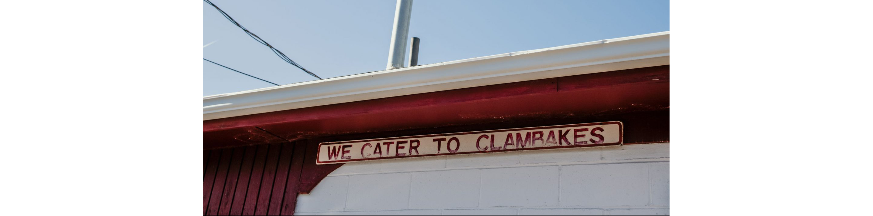 An old, faded sign of Woodman's Clam Strip.