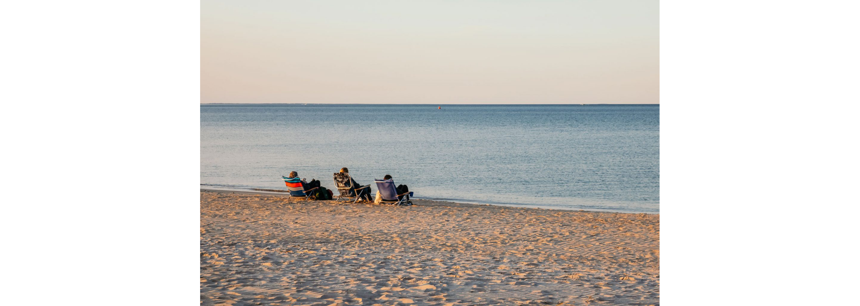 Three people relaxing in folding chairs on Crain's Beach.