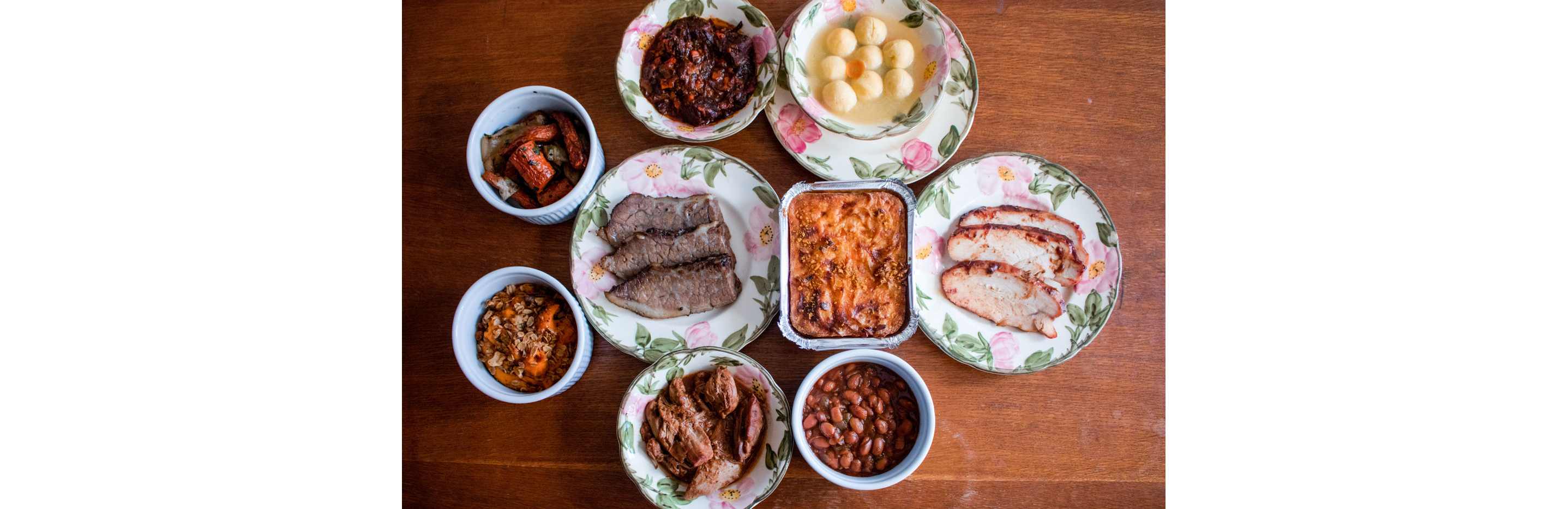 A table filled with decadent Jewish eats in served in floral china.