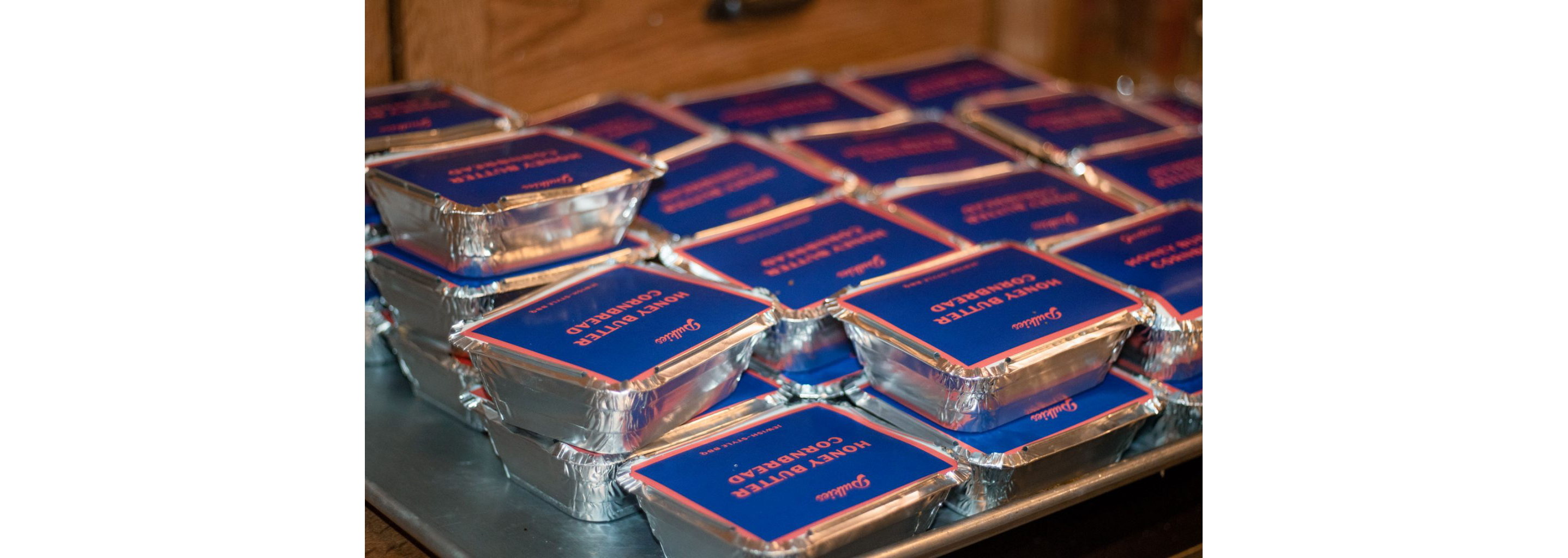 A series of sealed foil containers filled with honey butter cornbread.