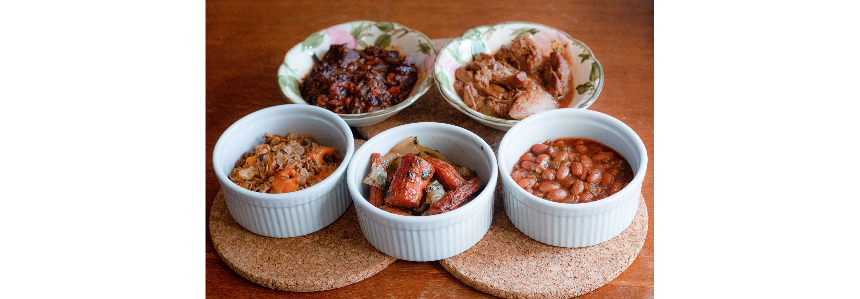 Small porcelain dishes of brisket, tzimmes and other delicious eats.