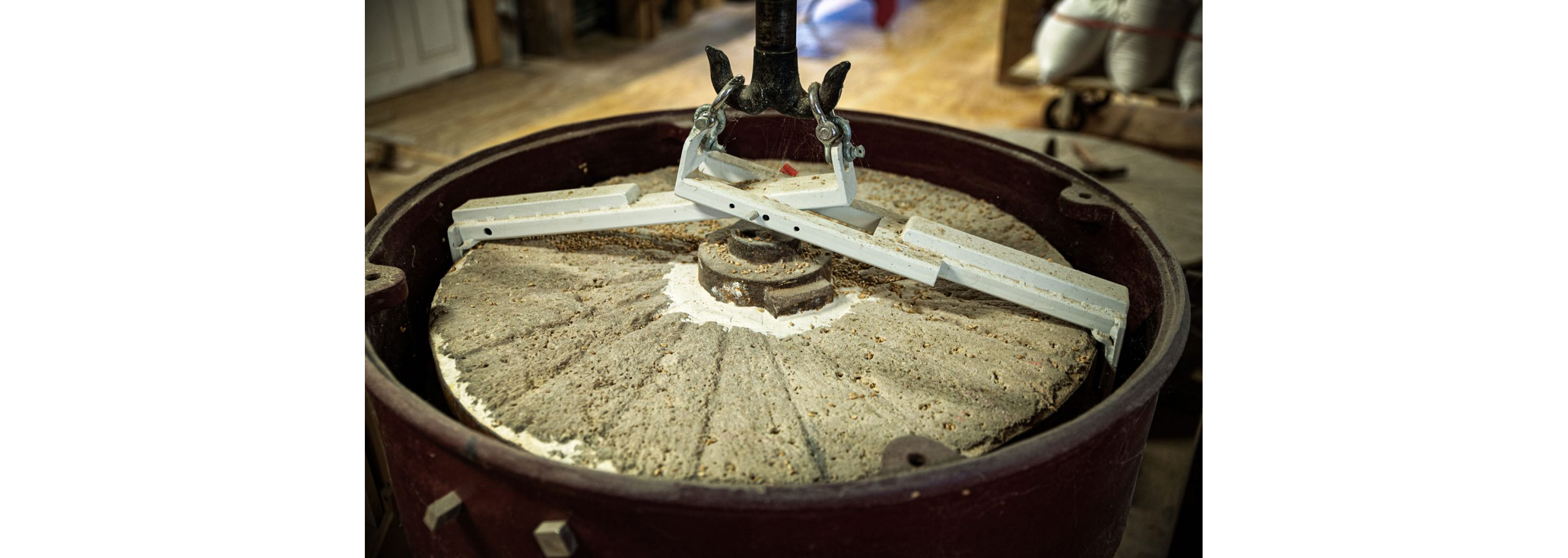 The heavy stone of a grain mill covered in residual grain.