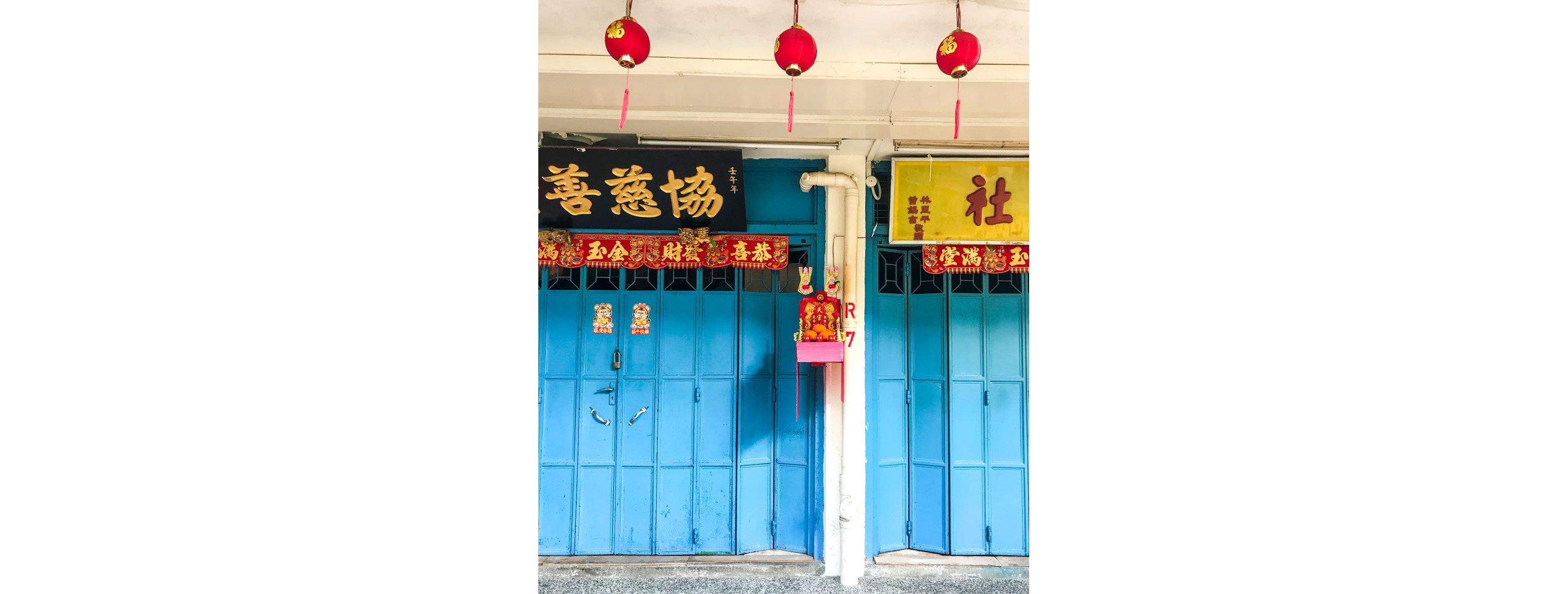 Exterior of a home with Lunar New Year decorations and offerings hanging from the blue doors.
