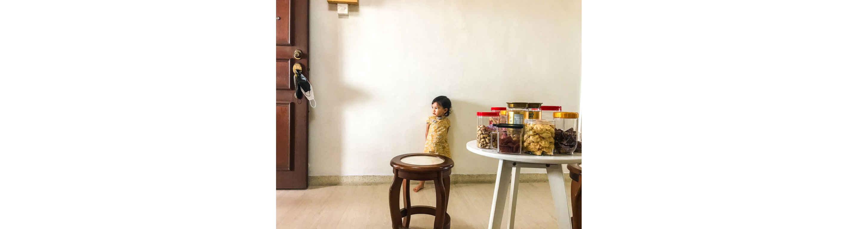 A child standing behind a stool and table with assorted treats in different containers.