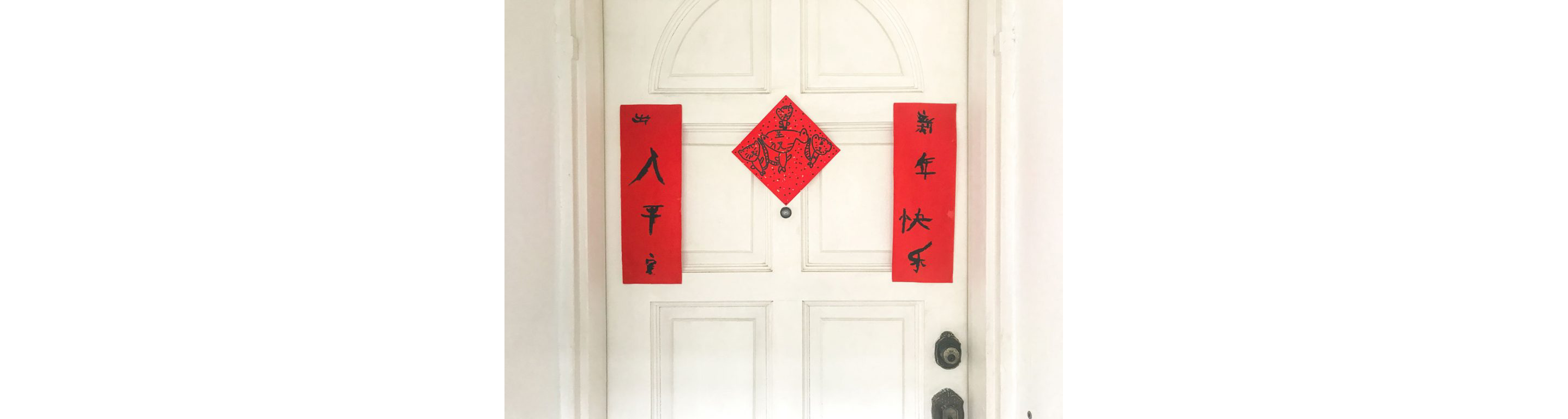 A white door with Lunar New Year decorations hanging from it.