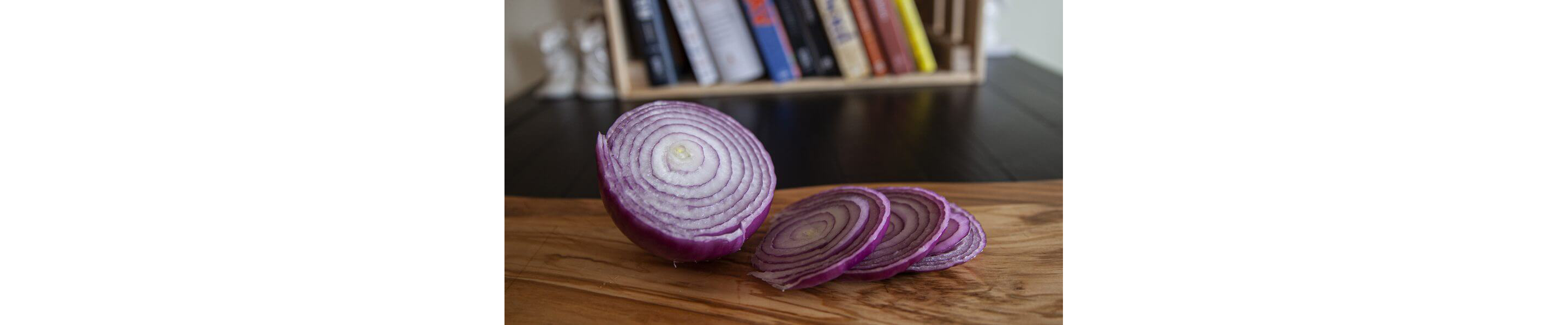 A sliced red onion resting on a wooden cutting board.