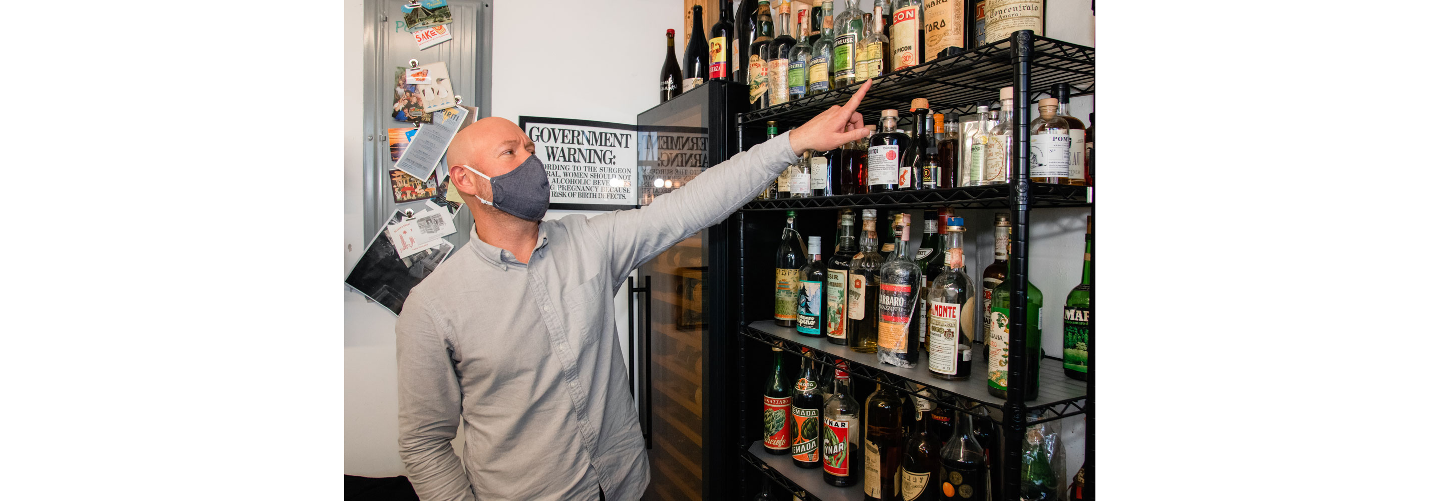 Aaron Sing Fox pointing out liquor bottles of Forthave Spirits.