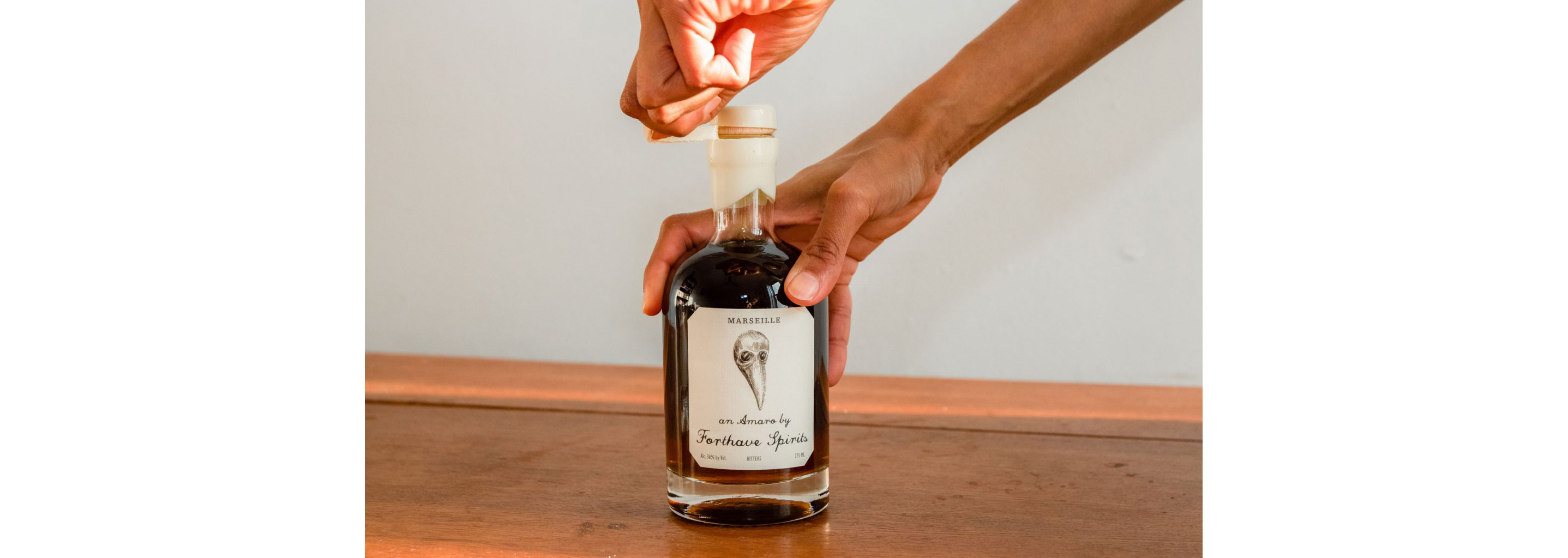 A person unwrapping the cork of a Forthave Spirit bottle.