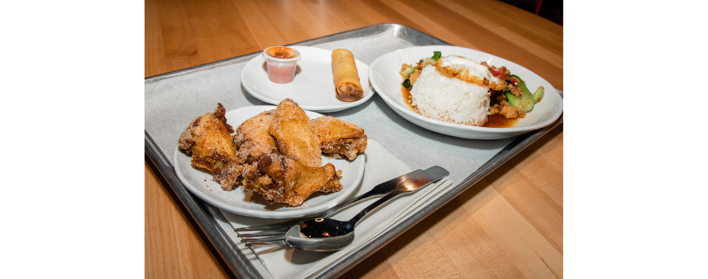 A tray of fried chicken wings and Thai food.