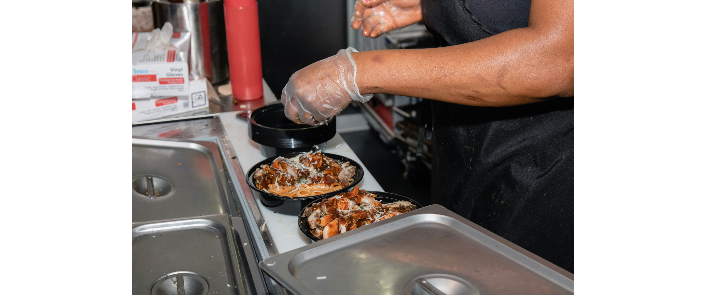 A person serving containers of Jamaican food.