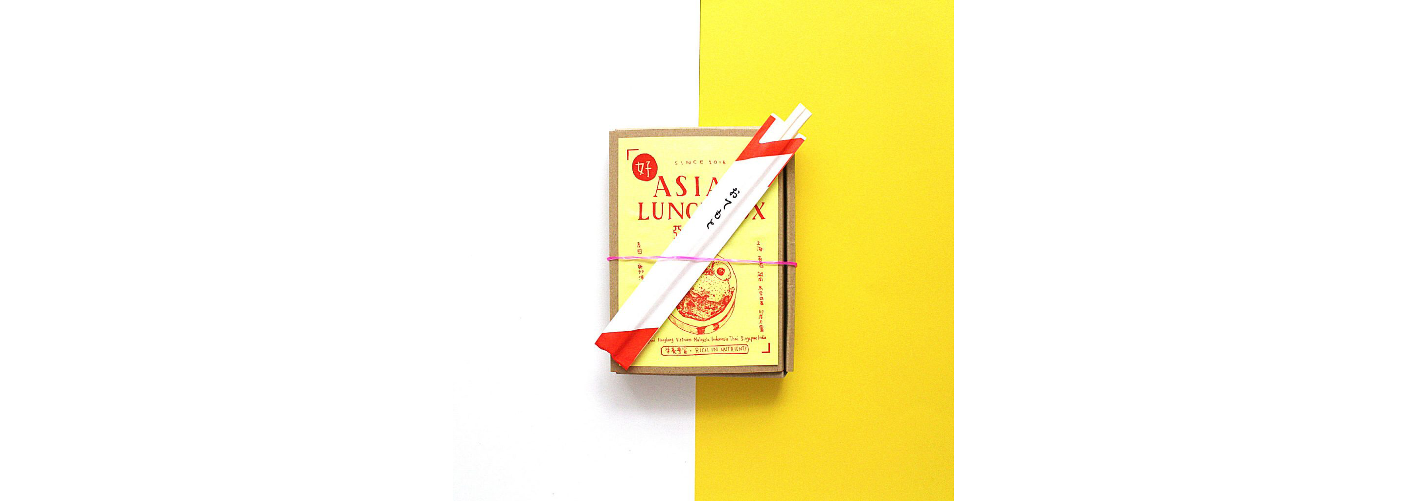A cardboard lunchbox with chopsticks resting on top.