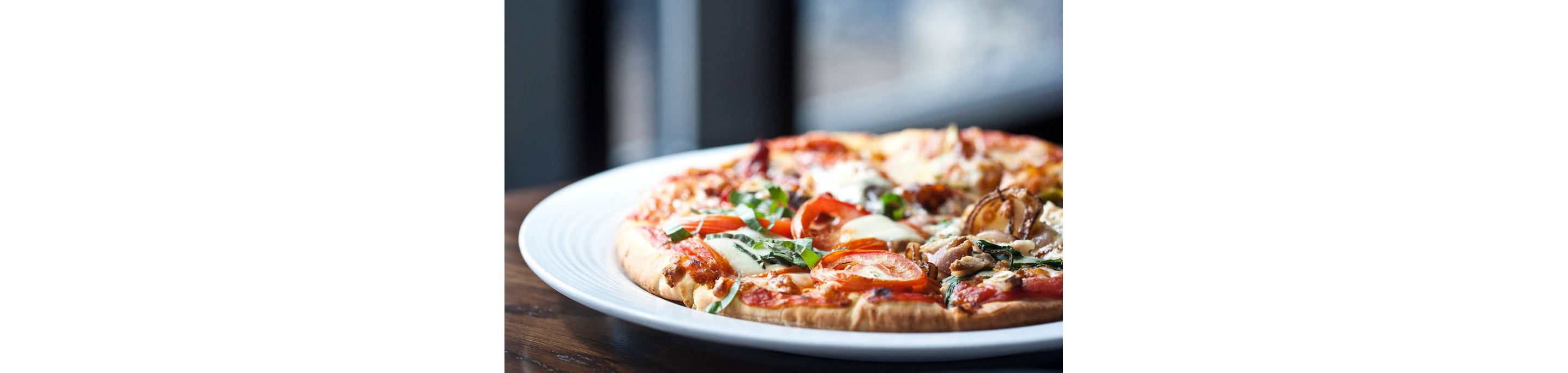 A freshly made pizza cooling off on a clean, white plate.