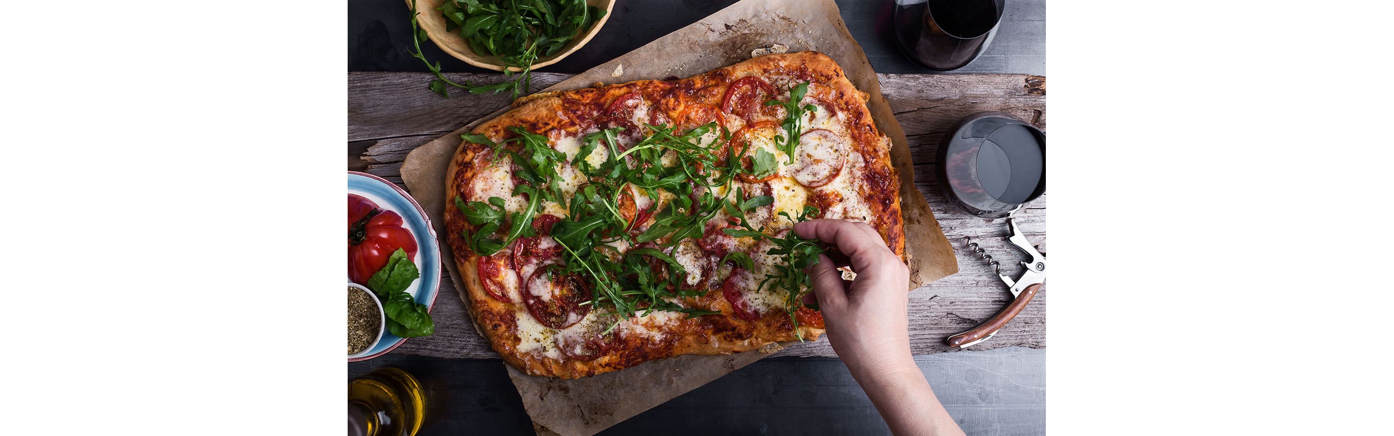 A freshly made flatbread pepperoni pizza sprinkled with arugula.