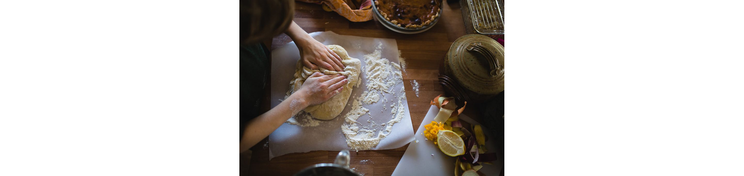 A person gently working dough with flour on parchment paper.