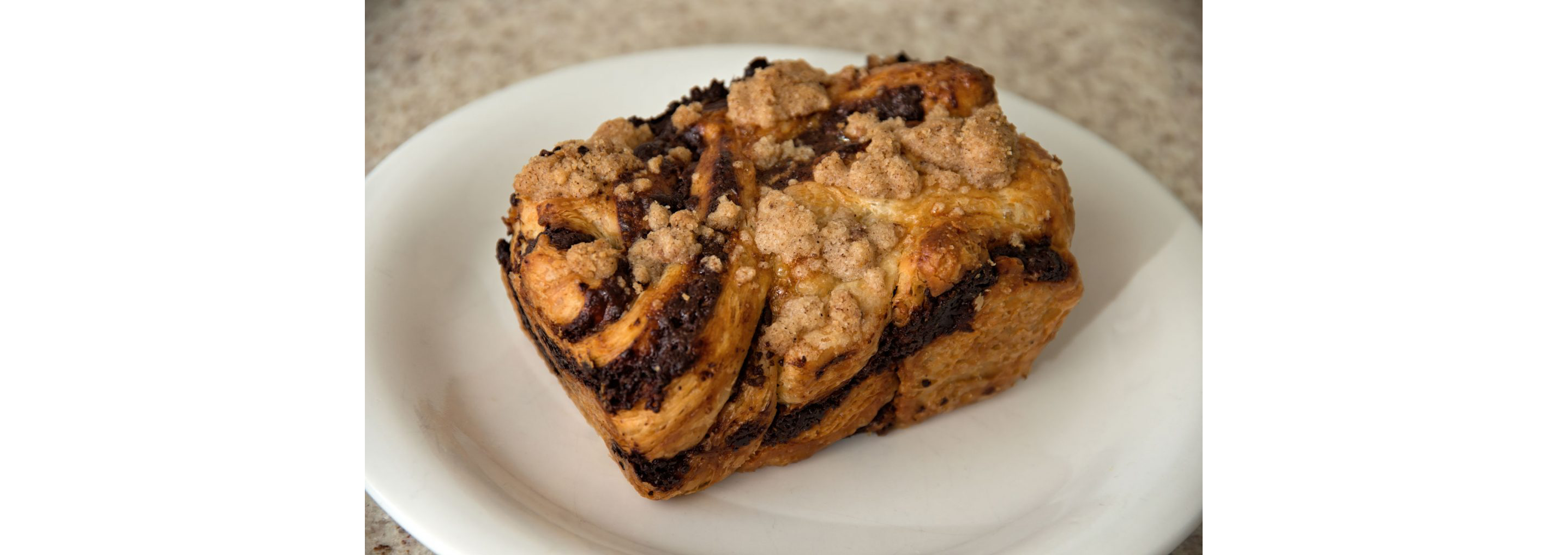 Chocolate babka bread on a clean, white plate.