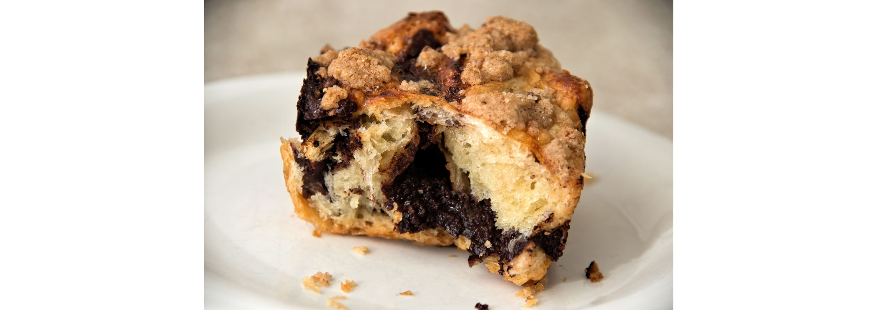 A half-eaten slice of chocolate babka bread on a white plate.