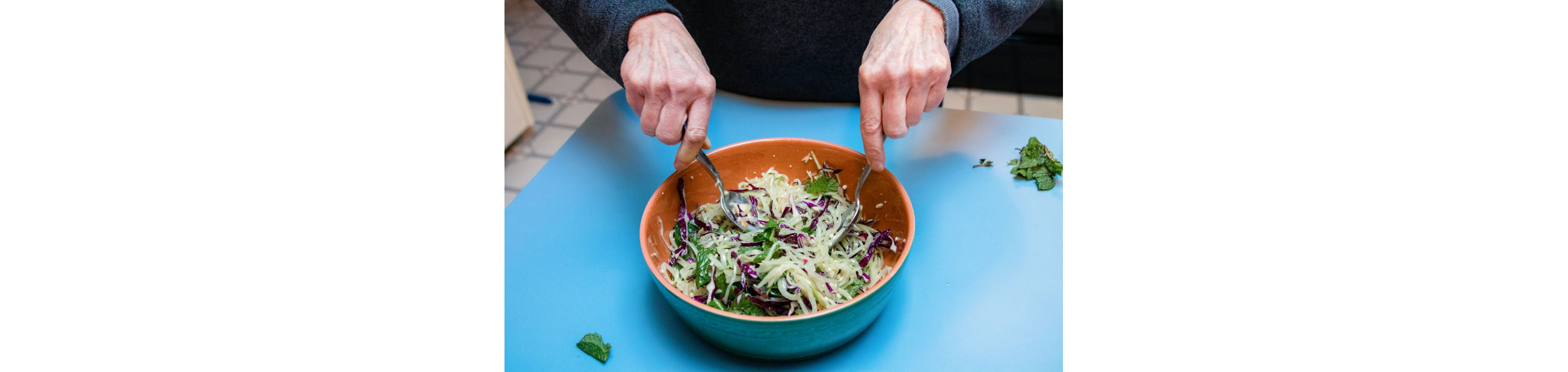 A person mixing together Spicy Green Papaya Slaw from Myers + Chang.