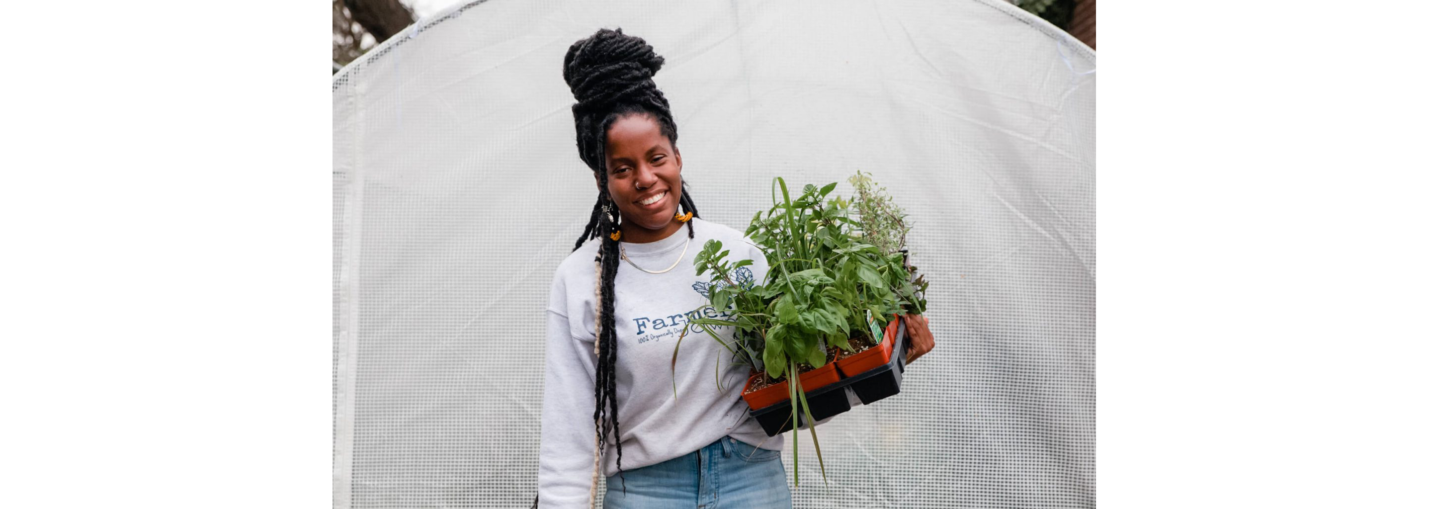 Christa holding a tray of plants as she smiles for a photo.