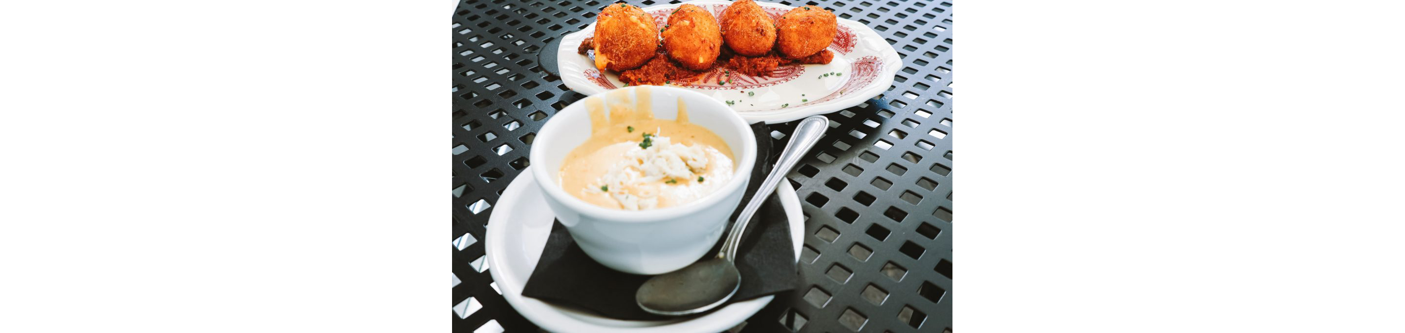 A dish of hushpuppies next to a small, delicate bowl.