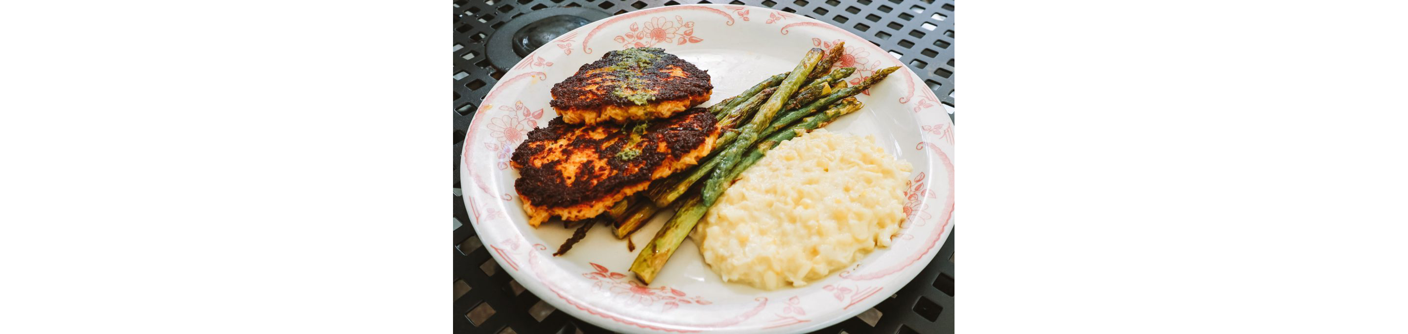 An ornate dinner plate filled with freshly cooked meat, asparagus and other sides.