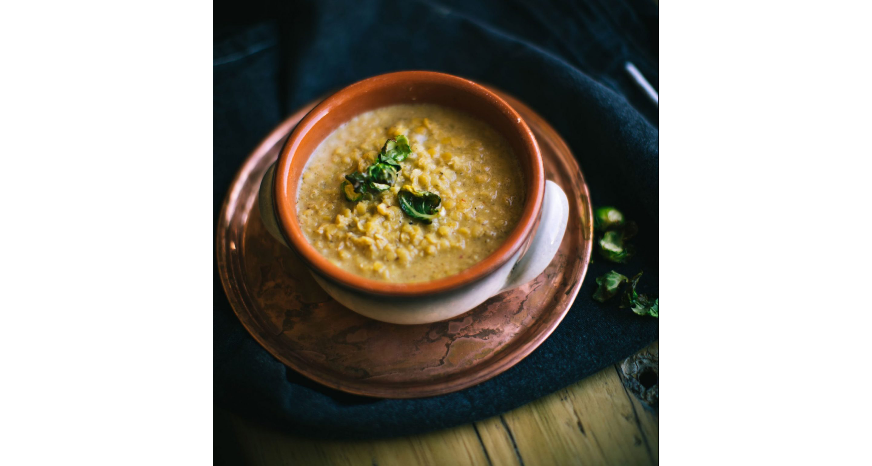 A light lentil soup in a bowl resting on an intricate plate.