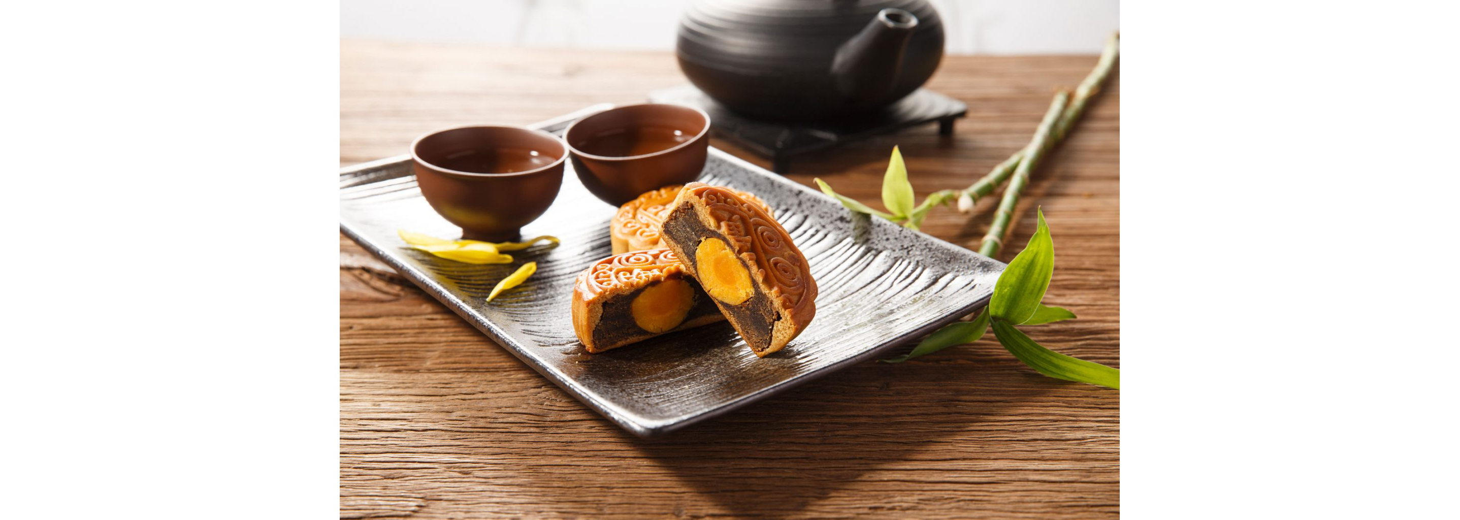 A set of mooncakes resting on a dark, rectangular plate.