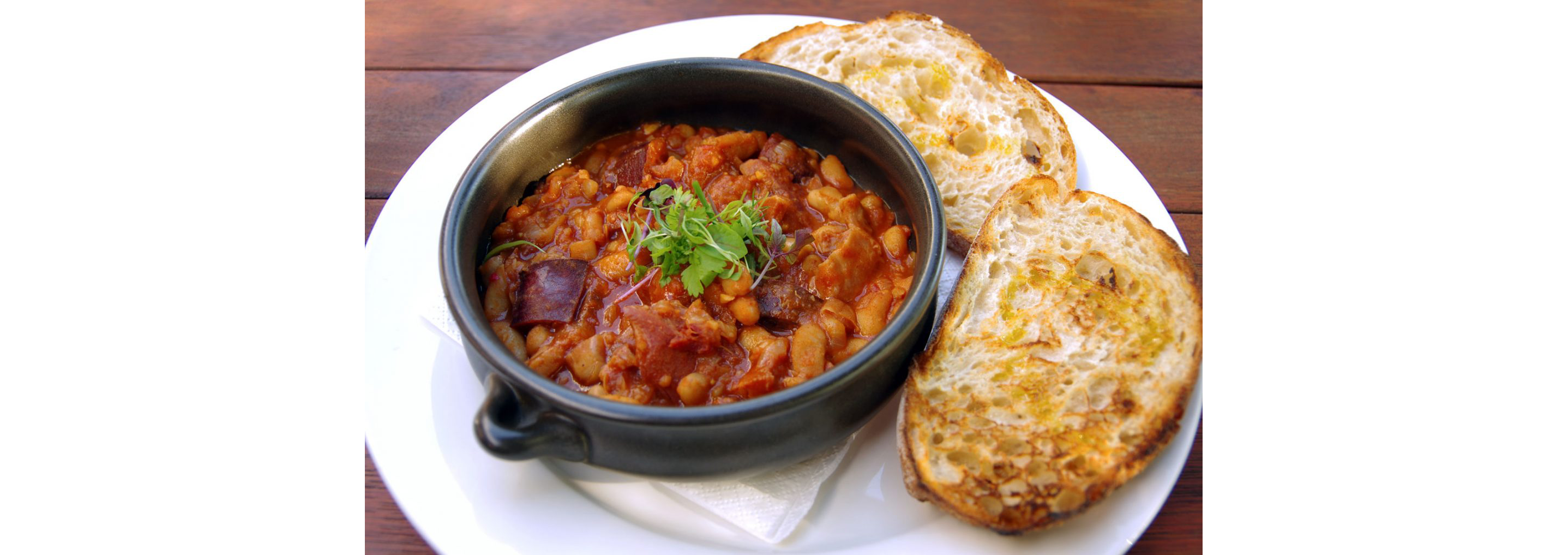 A black bowl filled with spicy New Orleans red beans and rice with a side of toasted bread.