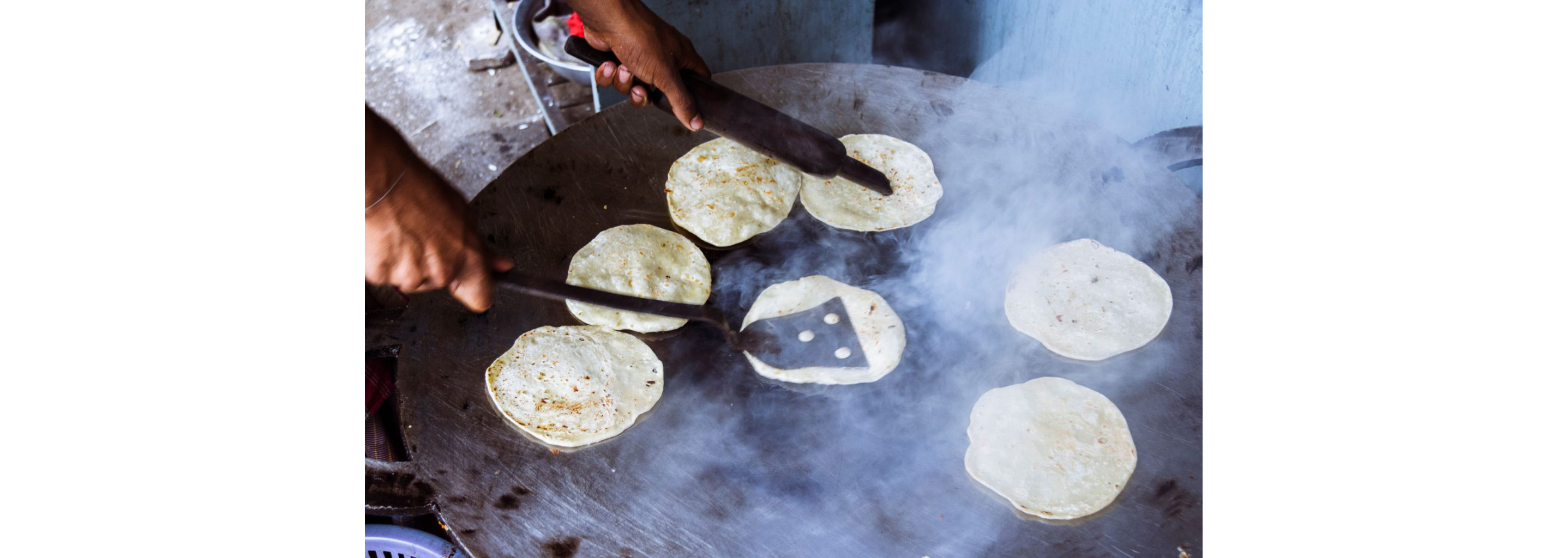 A person cooking small paratha flat bread.