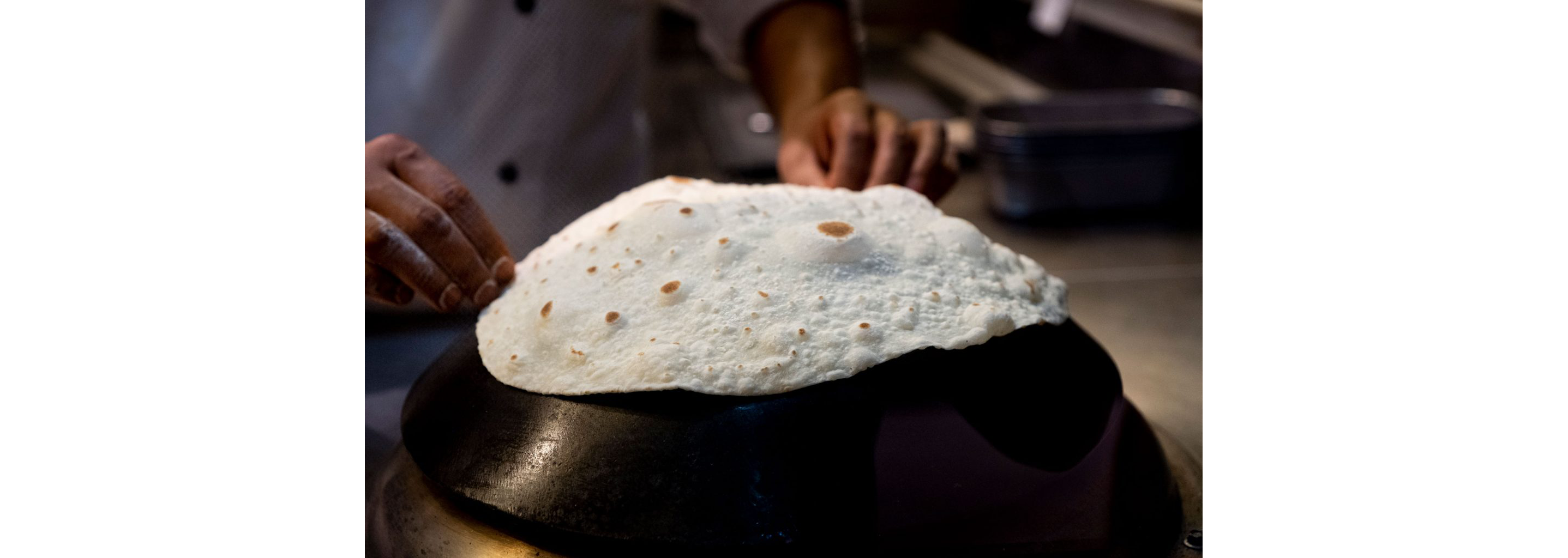 A person cooking paratha flat bread.