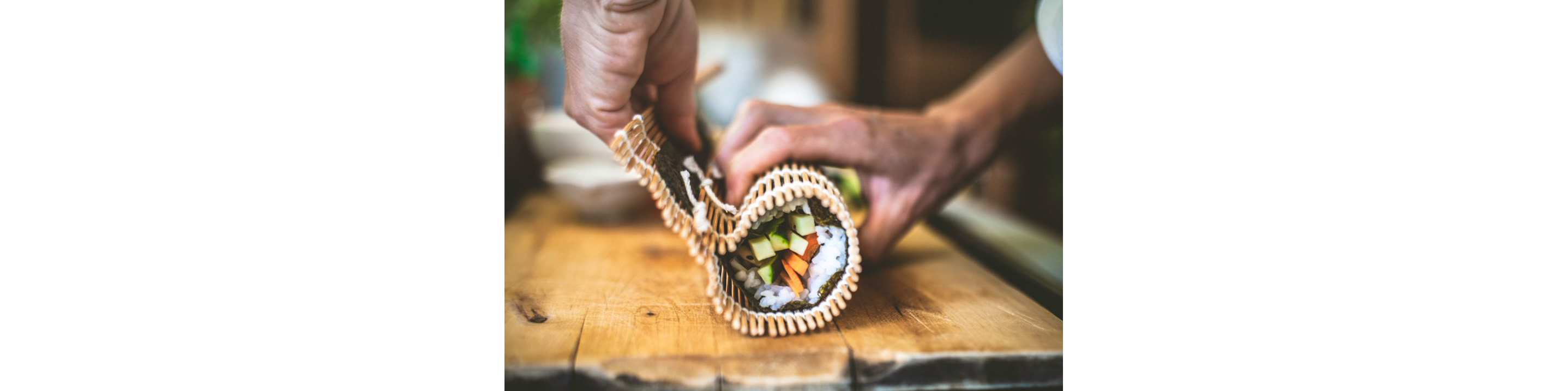 Fresh sushi being wrapped together using a bamboo rolling mat.