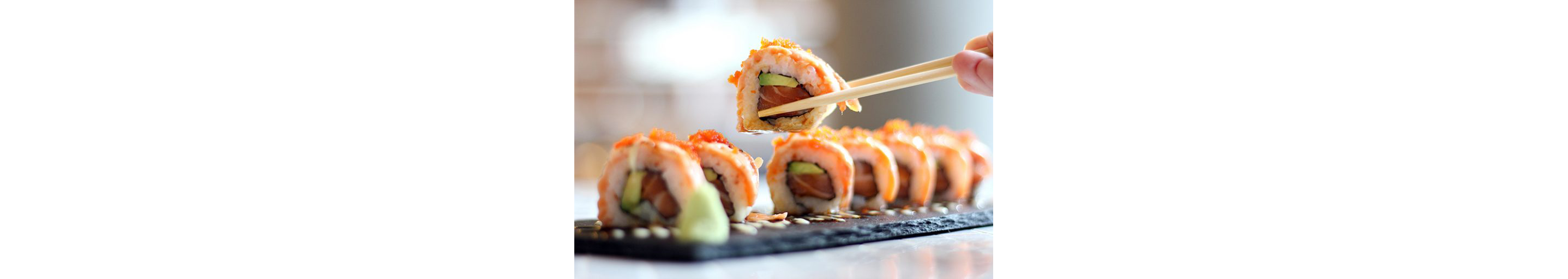 Wooden chopsticks lifting up a single, delicate roll of sushi.