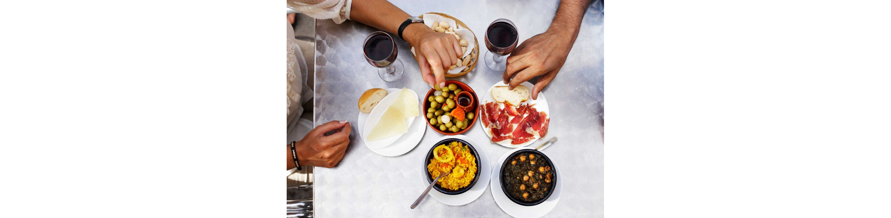 Friends gathered around a table filled with glasses of red wine and fine eats.