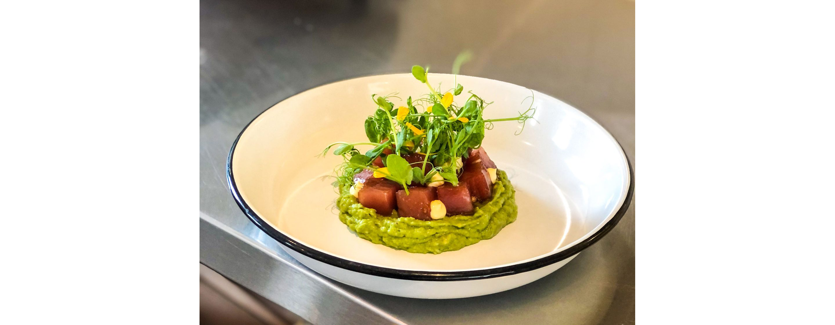 A fresh plate of ahi tuna resting on avocado.