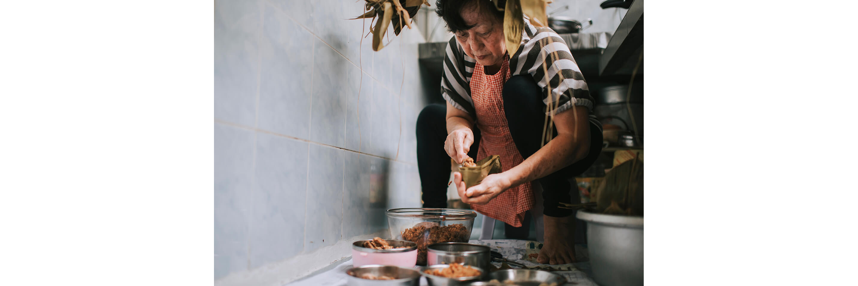 A woman stuffing rice into pocketed bamboo leaves.