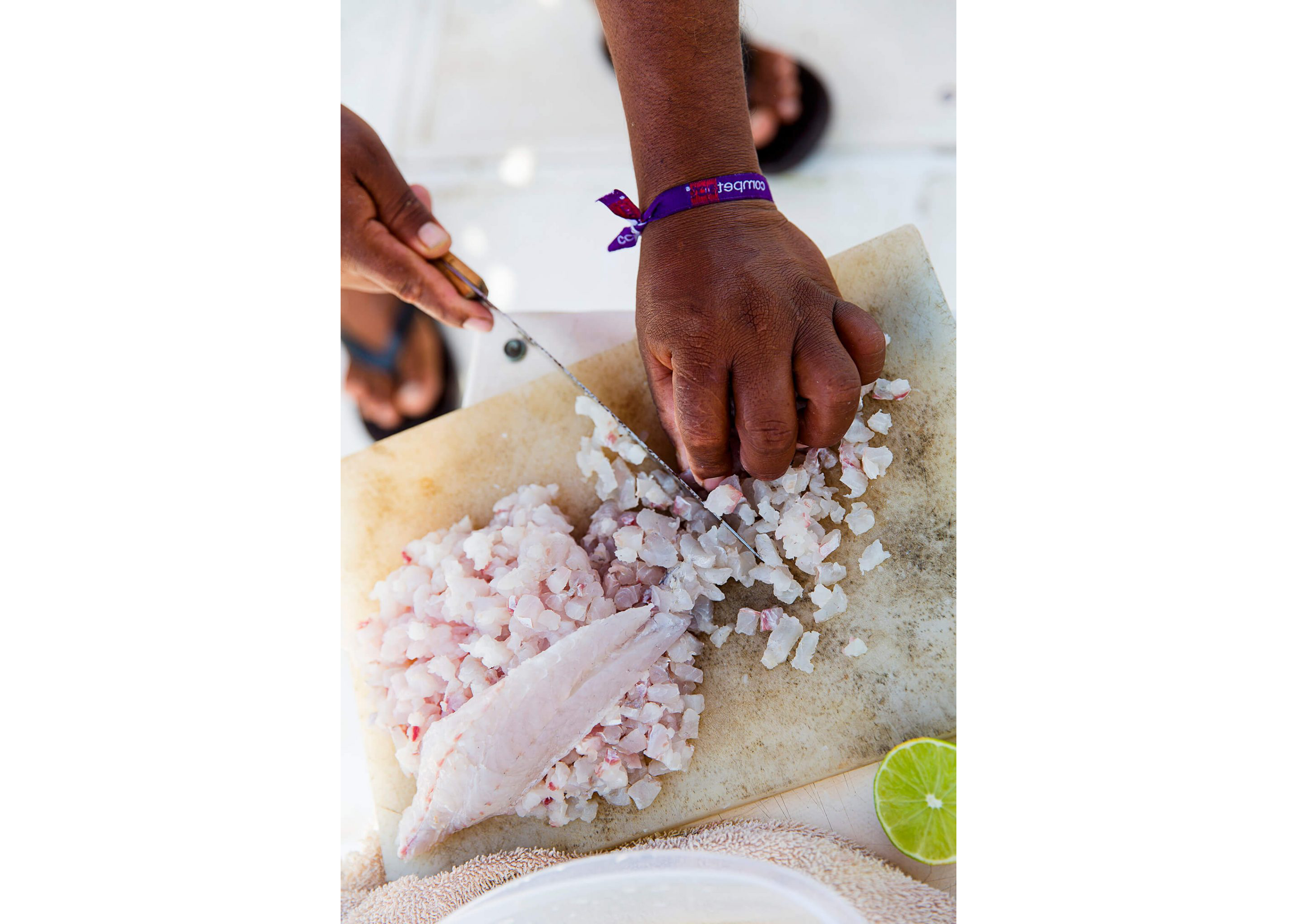 A person dicing up fresh fish on a wooden cutting.