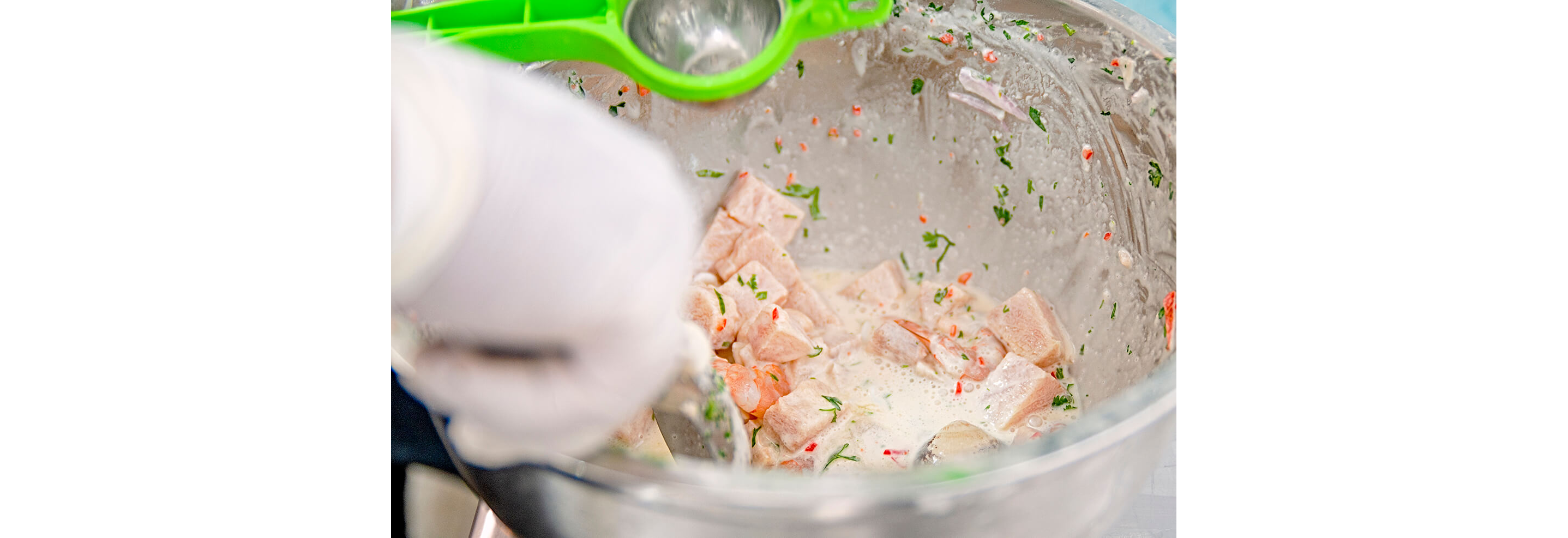 Ceviche being freshly made and seasoned in a large glass bowl.