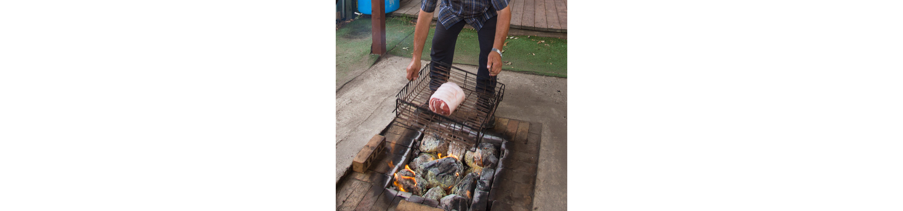 A man preparing Maori hangi: food wrapped in wet cloth in a metal basket.