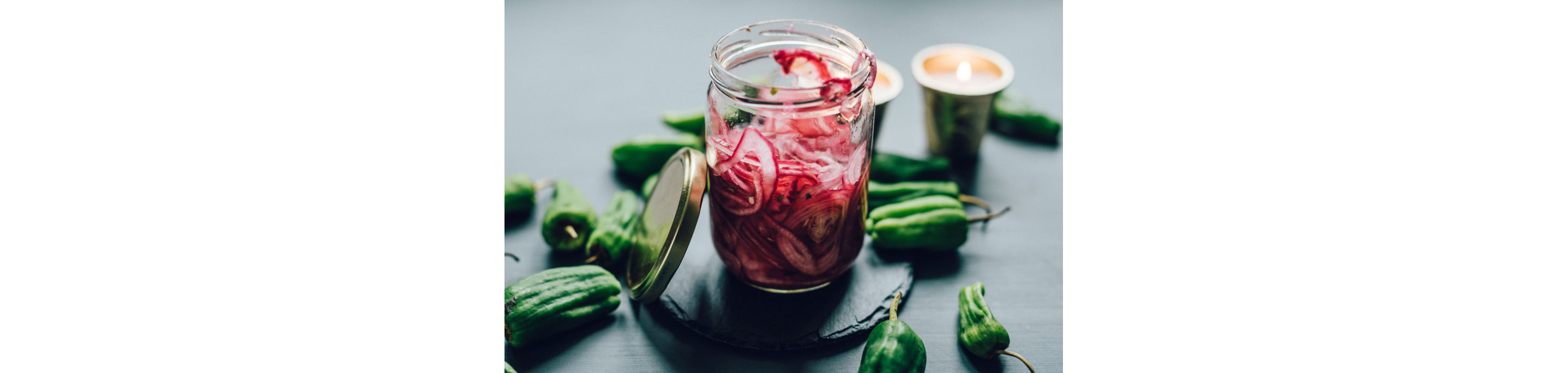 A small, open glass jar filled with sliced, pickled red onion.