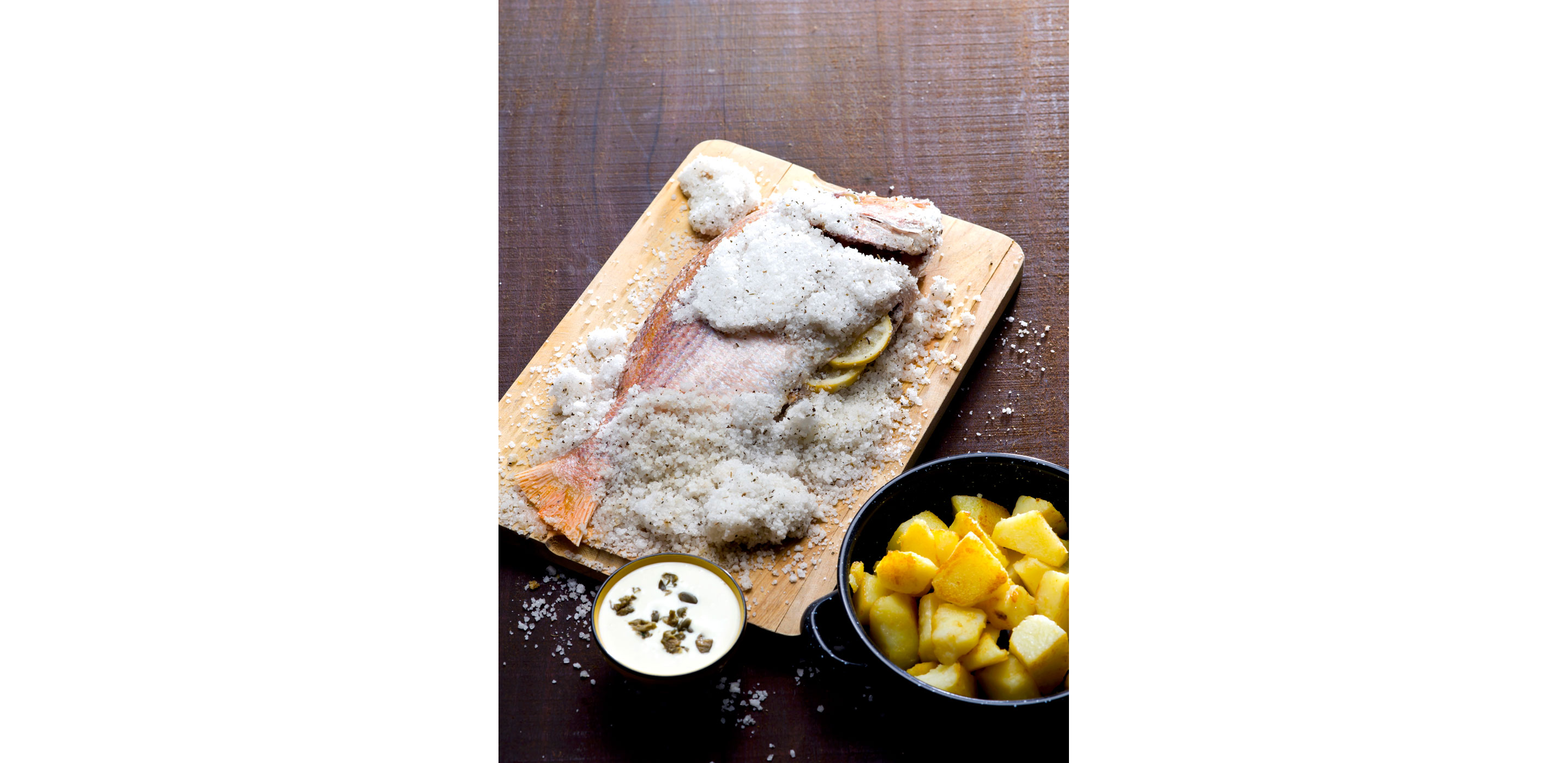 A whole fish in the process of being salt-crusted.